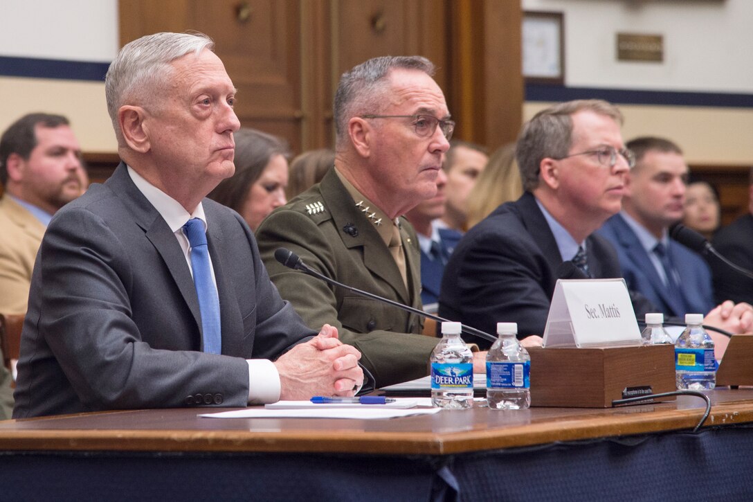Defense Secretary James N. Mattis and the chairman of the Joint Chiefs of Staff sit behind a desk.