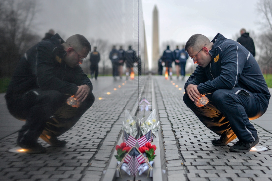 A sailor leans over near the Vietnam Veterns Memorial.