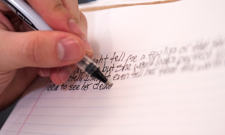 U.S. Air Force Airman 1st Class John Cone writes and reads one of his slam poetry pieces.