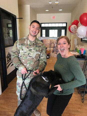 U.S. Army Sgt. Eduardo Cortes, left, a Food Inspection Specialist assigned to the veterinary treatment center here, introduces his dog, Pepper, to Madalyn Frietag, a Joint Base Charleston Family Housing Relocation Service Specialist, while celebrating National Pet Day, April 11, 2018.