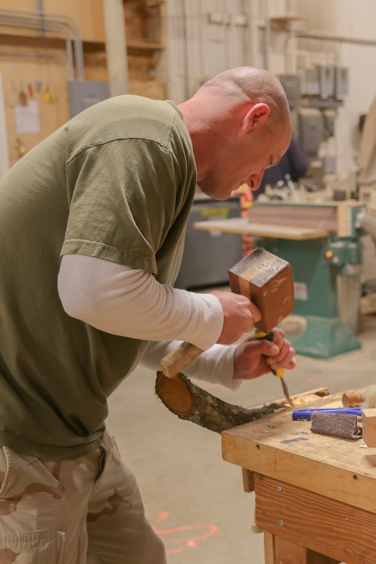 Soldier carves a wooden spoon as part of a mentoring program.