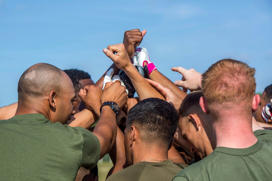 Marines gather together and hold their hands in the air.