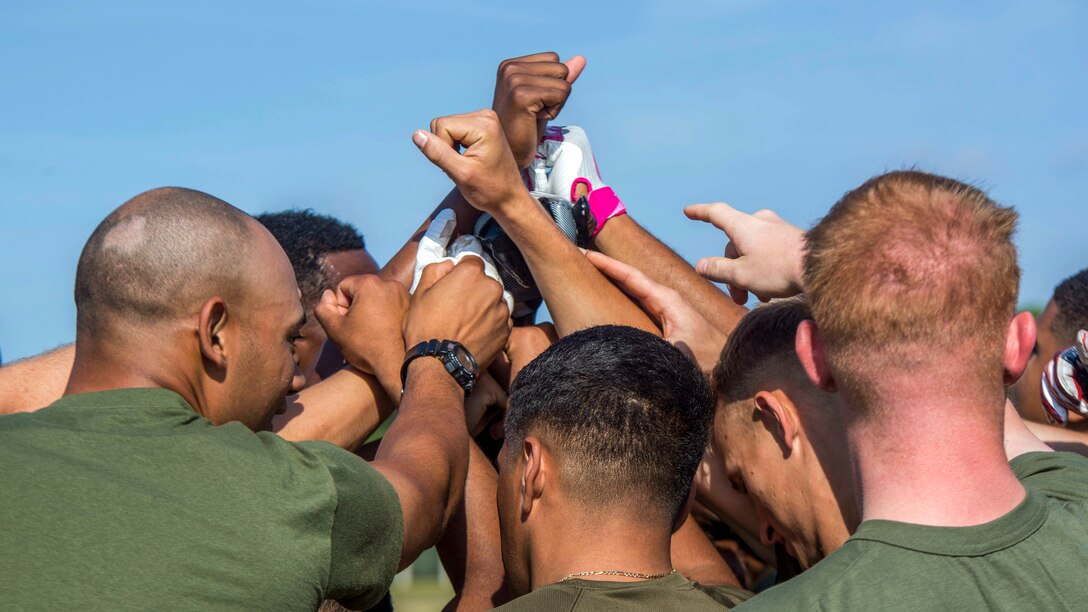 Marines gather together and hold their hands in the air.