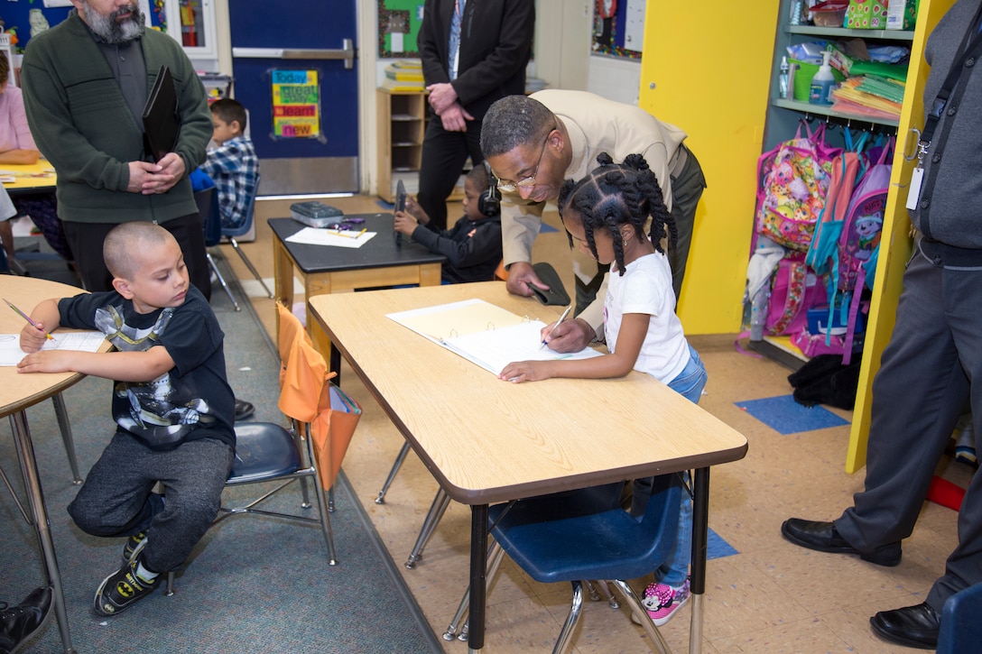 A student at Cameron Elementary School watches as Col. Sekou Karega, commanding officer, MCLBB, signs her workbook during Karega’s tour of all of the schools in the Barstow Unified School District March 28.