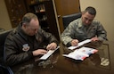 Col. David Berg, 55th Wing vice commander and Chief Master Sgt. Brian Kruzelnick, 55th Wing command chief, fill out a form in support of the Air Force Assistance Fund at the 55th Wing headquarters on Offutt Air Force Base, Neb., March 30, 2018.