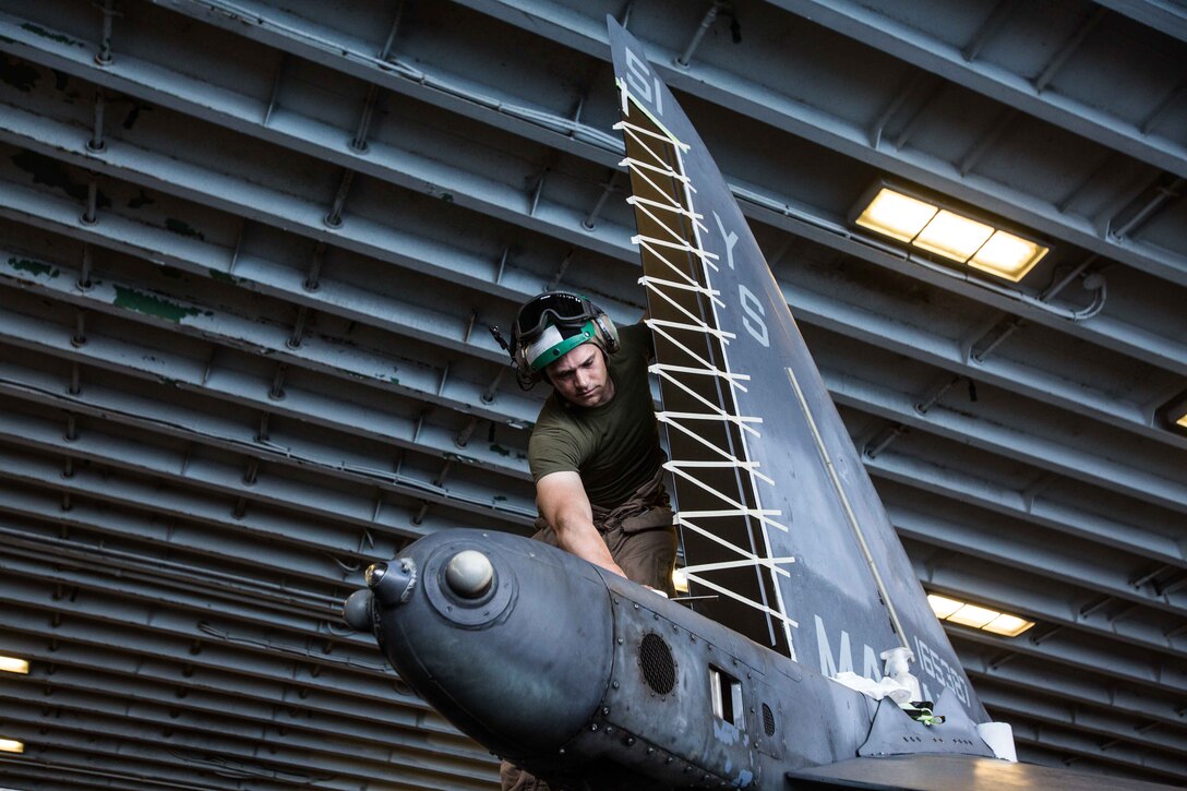 U.S. Marine Corps Staff Sgt. Johnathan B. Davis, the AV-8B Harrier airframes chief assigned to Marine Medium Tiltrotor Squadron (VMM) 162 (Reinforced), 26th Marine Expeditionary Unit (MEU), and a Mattoon, Illinois native, applies masking tape to the tail of an AV-8B Harrier prior to painting in the hangar deck of the Wasp-class amphibious assault ship USS Iwo Jima (LHD 7), April 11, 2018. The 26th MEU trains to sustain expeditionary readiness across a range of critical capabilities both afloat and ashore in order to be prepared to respond to crisis in the U.S. 5th Fleet Area of Operations. (U.S. Marine Corps photo by Cpl. Jered T. Stone/Released)
