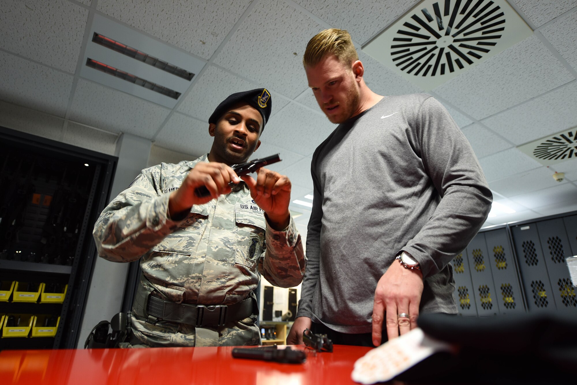 U.S. Air Force Tech. Sgt. Deandre Harrington, 86th Security Forces Squadron police services noncommissioned officer in charge, shows Kyle Rudolph, NFL Minnesota Vikings tight end, how to properly disassemble and clean an M9 handgun on Ramstein Air Base, Germany, April 6, 2018. Harrington explained to Rudolph that if proper care isn’t taken with a firearm, it may misfire when needed.