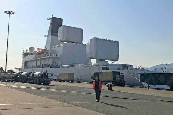 Maj. Christina Light, the Technical Operations Squadron Director of Operations with the Air Force Technical Applications Center, Patrick AFB, Fla., stands in front of the USNS Howard O. Lorenzen, a U.S. naval ship that hosts the $1.7 billion Cobra King radar platform.