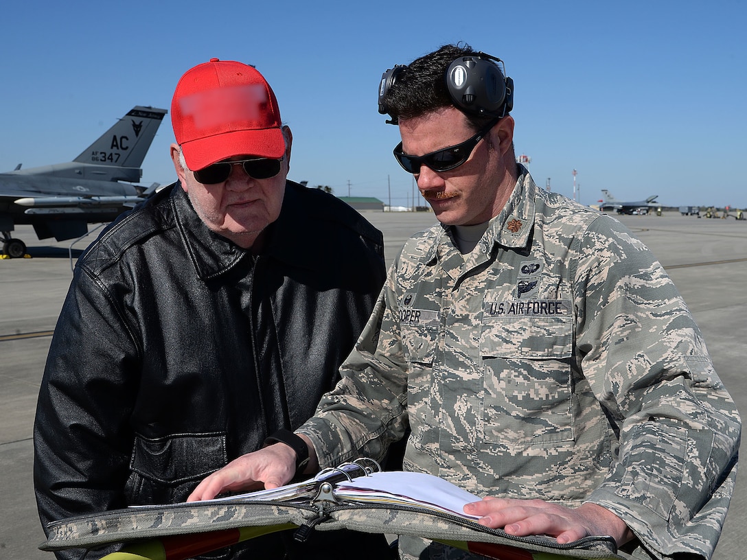 Father and son, one in Air Force uniform, look at a maintenance manual.