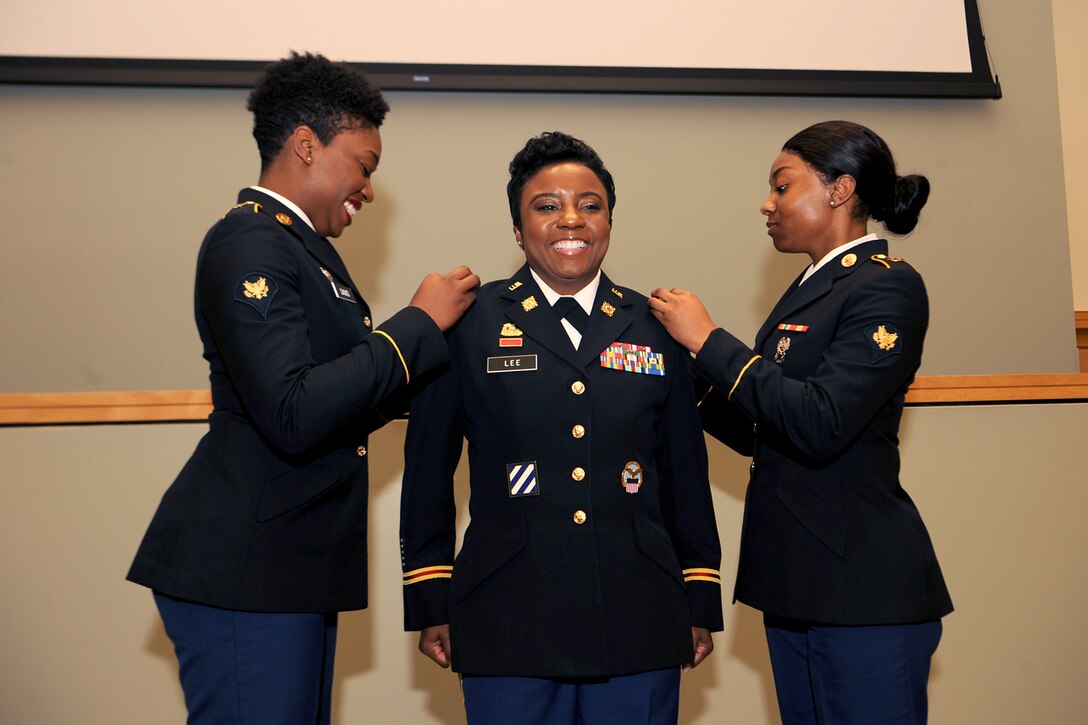 Army Spc. Nia Davis (left) and Army Spc. Raven Lee (right) affix the rank insignia to Army Lt. Col. Latrina Lee’s (center) uniform during her promotion ceremony April 6. The two specialists are the nieces of Lt. Col. Lee, DLA Troop Support chief of current operations.