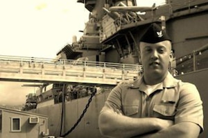 A sailor stands next to a ship.