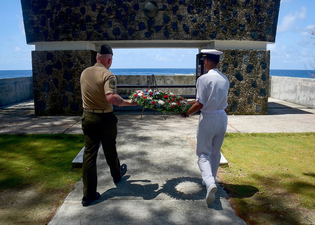 A Marine and a sailor lay a wreath.