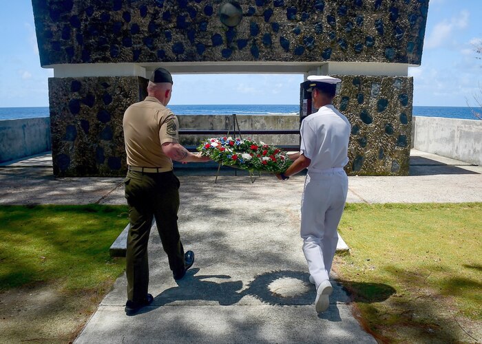 An U.S. Marine and a Japanese Maritime Self Defense Force member carry a wreath.