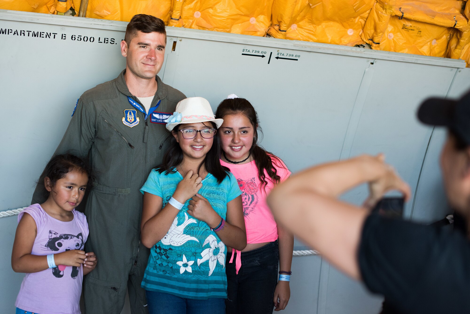 U.S. Air Force Staff Sergeant Luke Findley, 79th Air Refueling Squadron Boom Operator, Travis Air Force Base, California, poses for a photograph with members of the Chilean public during the FIDAE 2018 international airshow in Santiago, Chile, April 8, 2018.  U.S. airmen participated in a variety of activities during the air show, including subject matter exchanges with the Chilean Air Force, aerial demonstrations, and interaction with the local community.  (U.S. Air Force photo by Staff Sgt. Danny Rangel)