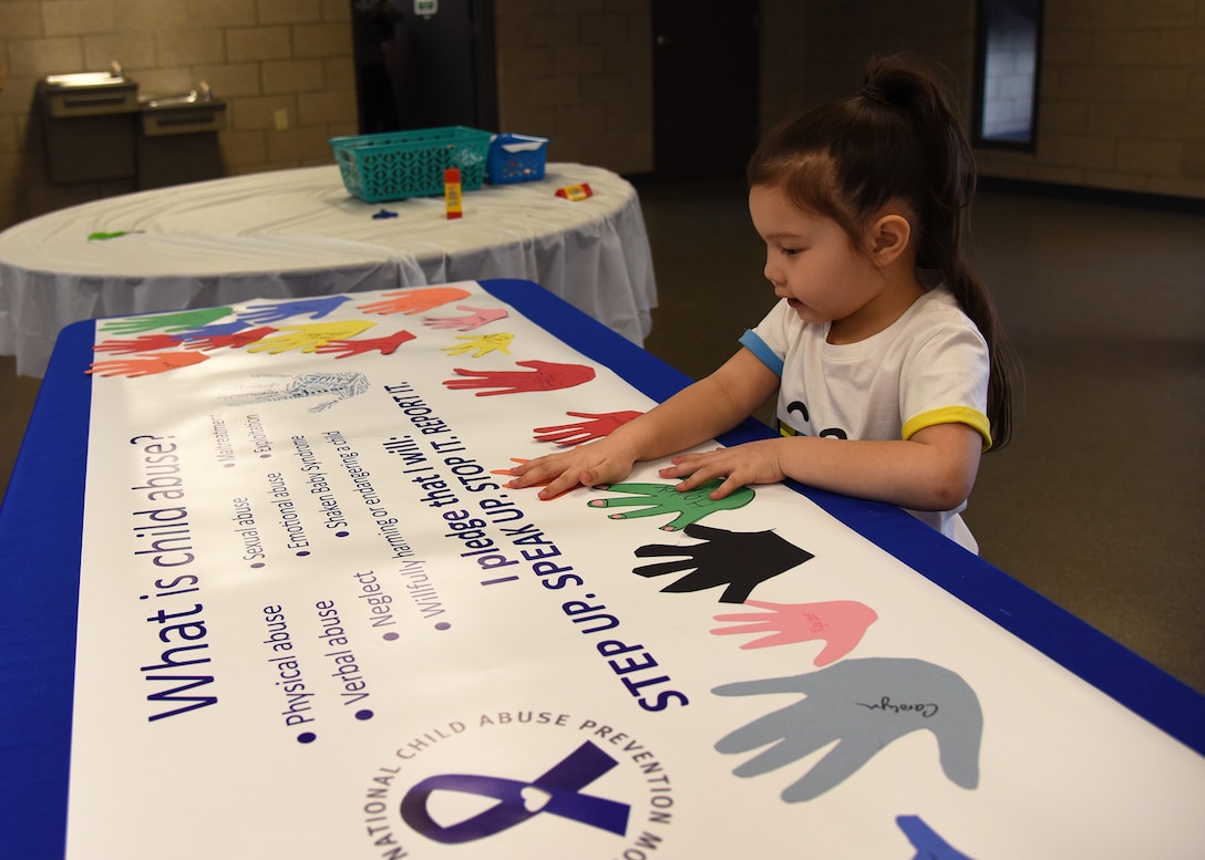 Aeryn Iglesias glues down a paper cut-out of her hand on a banner Apr. 10, 2018, on Grand Forks Air Force Base, N.D. Iglesias and other members at Grand Forks AFB, pledged their commitment against child abuse to, "Step up. Speak up. Stop it. Prevent it." April is nationally-observed as Child Abuse Prevention Month. (U.S. Air Force photo by Staff Sgt. Desiree Economides)