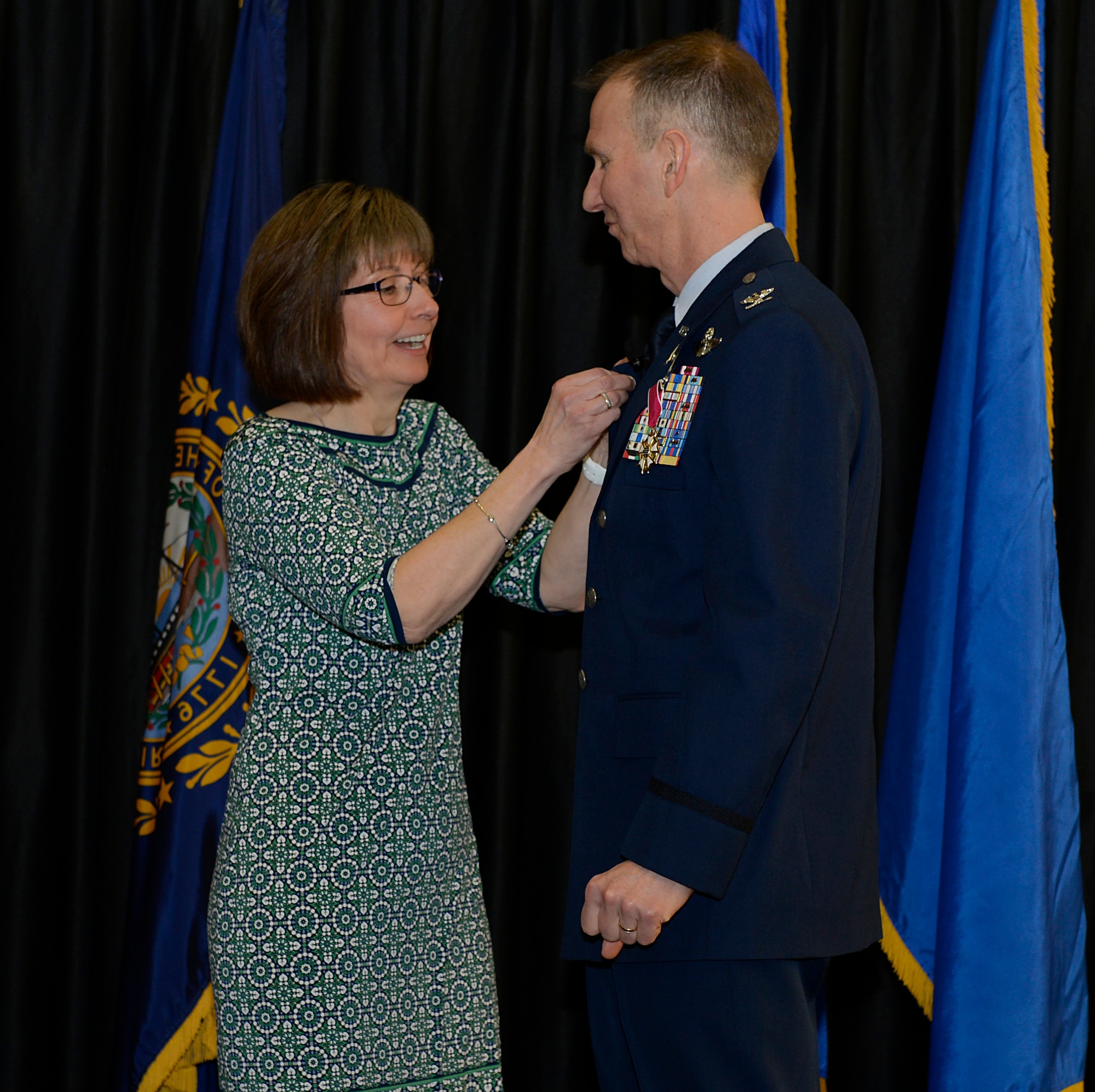 Mary Ellen, wife of Col. James P. Ryan, retired, 157th Air Refueling Wing commander, pins his retirement pin to his jacket on April 07, 2018 at Pease Air National Guard Base, N.H. Ryan retired after more than 30 years of service. (N.H. Air National Guard photo by Airman 1st Class Victoria Nelson)
