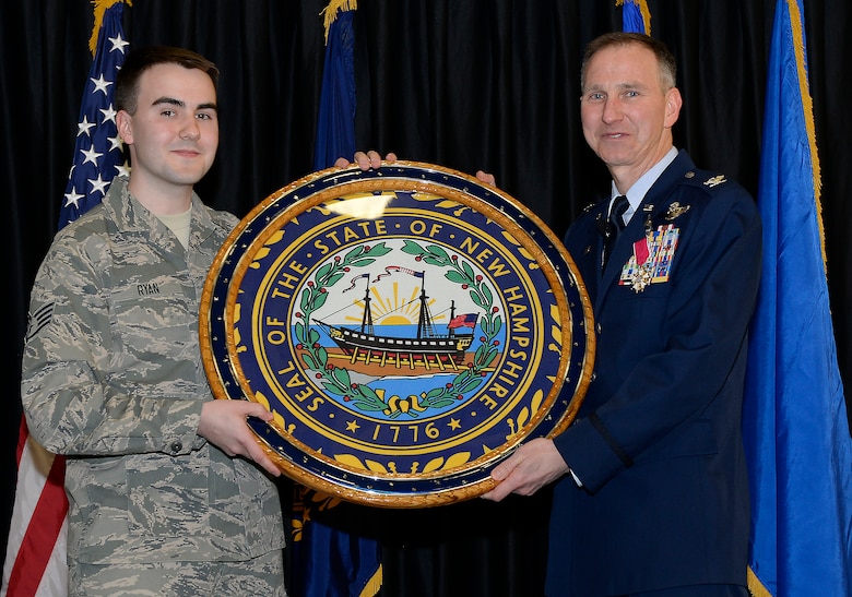 Col. James P. Ryan, retired 157th Air Refueling Wing commander, receives a retirement gift from his son, Staff Sgt. James Ryan, during his retirement ceremony on April 07, 2018 at Pease Air National Guard Base, N.H. Ryan retired after more than 30 years of service. (N.H. Air National Guard photo by Airman 1st Class Victoria Nelson)