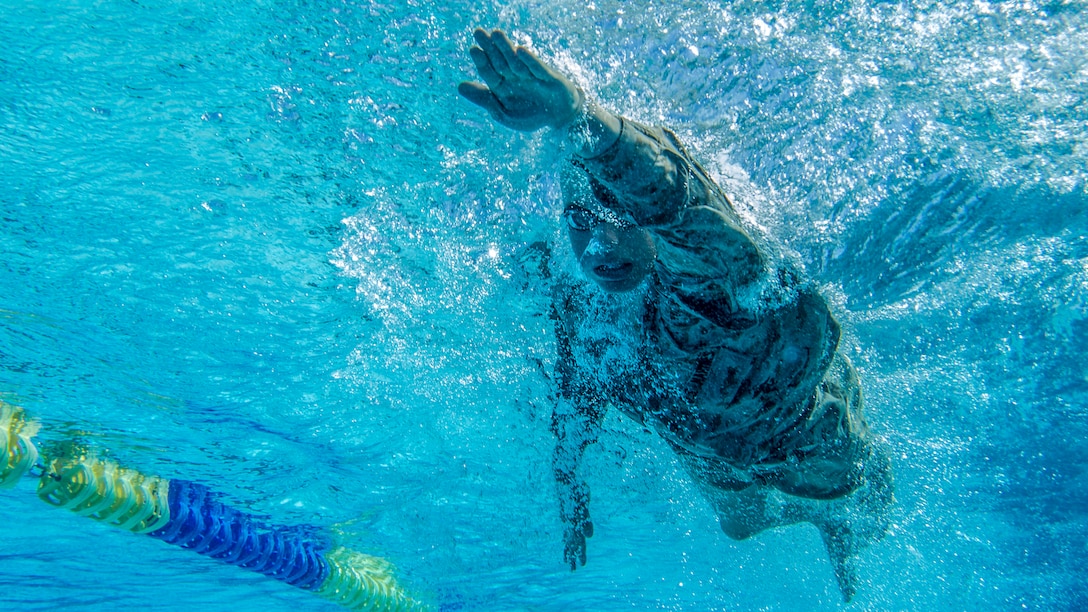 A Marine swims freestyle in a pool.
