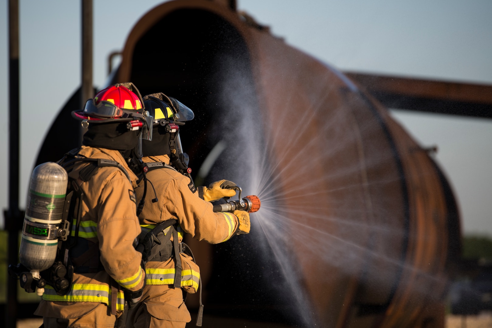 Firefighters from Joint Base San Antonio-Randolph prepare a fire hose before entering a mockup aircraft April 11, 2018 at the Camp Talon fire training grounds on JBSA-Randolph. The training offers firefighters the opportunity to train with live fire to get as close to a real-life scenario as possible. (U.S. Air Force photo by Senior Airman Gwendalyn Smith)