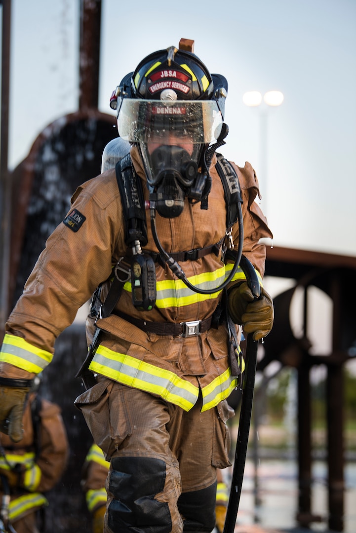 A firefighter from Joint Base San Antonio-Randolph carries a hand line during training April 11, 2018 at the Camp Talon fire training grounds on JBSA-Randolph. The training offers firefighters the opportunity to train with live fire to get as close to a real-life scenario as possible. (U.S. Air Force photo by Senior Airman Gwendalyn Smith)