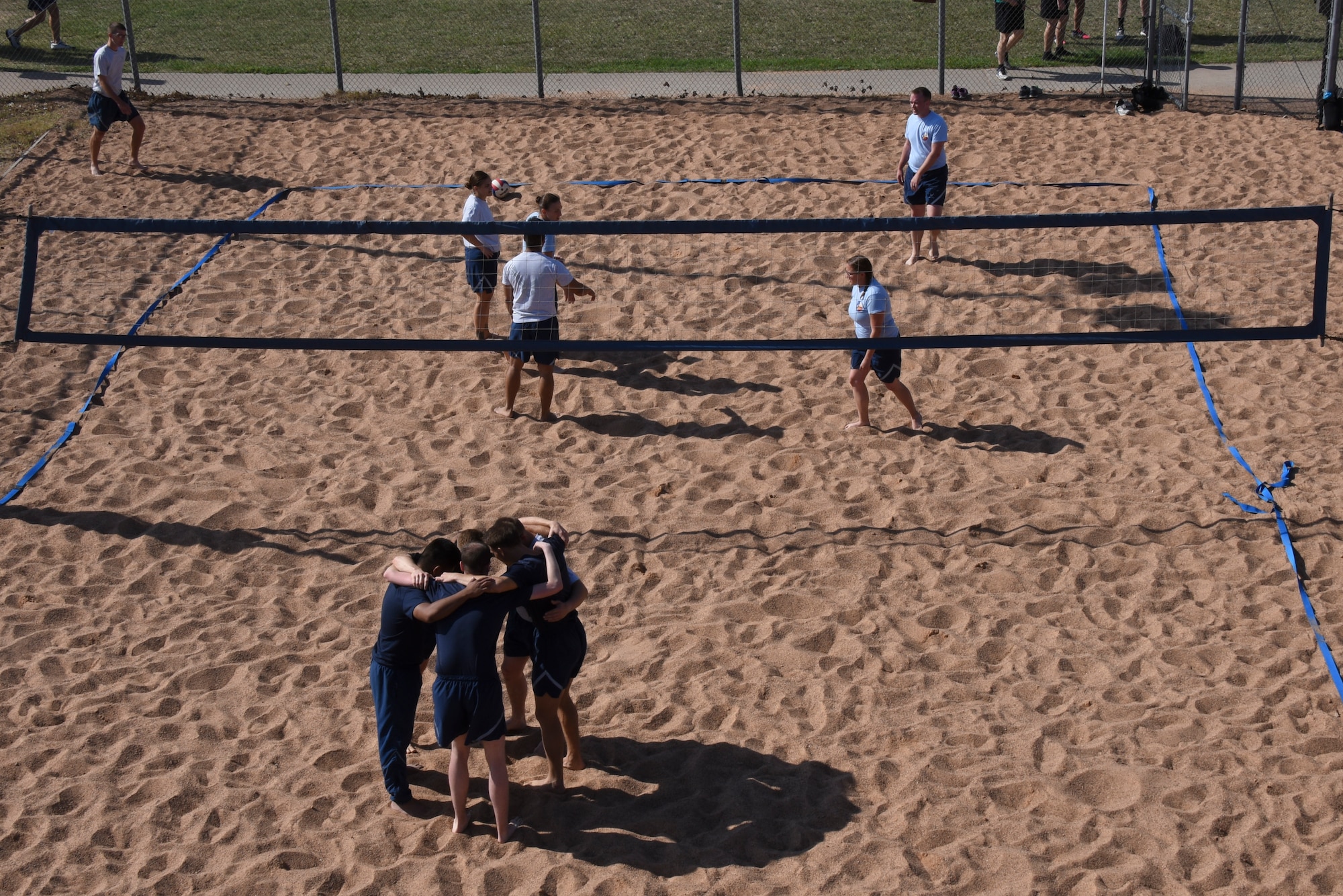 Airmen huddle before beginning a sand volleyball match during the Sports Day at Mathis Fitness Center on Goodfellow Air Force Base, Texas, April 13, 2018. Many different units from Goodfellow competed, but the 315th Training Squadron took first place in this category.