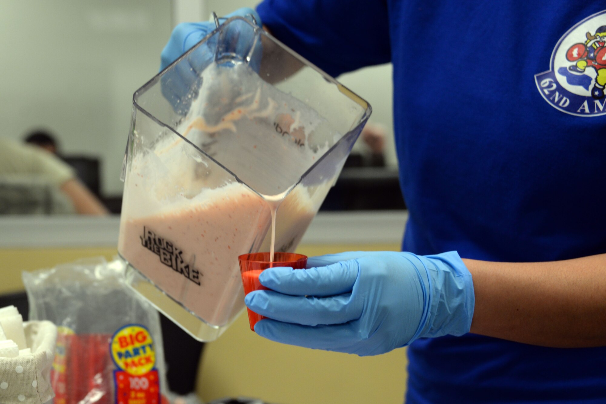 Yyolany Caffery, 56th Aerospace Medicine Squadron health promotions coordinator, pours a smoothie into sampling cups during the smoothie bike demonstration at Luke Air Force Base, Ariz., April 5, 2018. The bike demonstration promotes National Nutrition Month, which the 56th MDG is using to inspire Thunderbolts to eat healthier and promote overall wellness. (U.S. Air Force photo by Senior Airman Devante Williams)