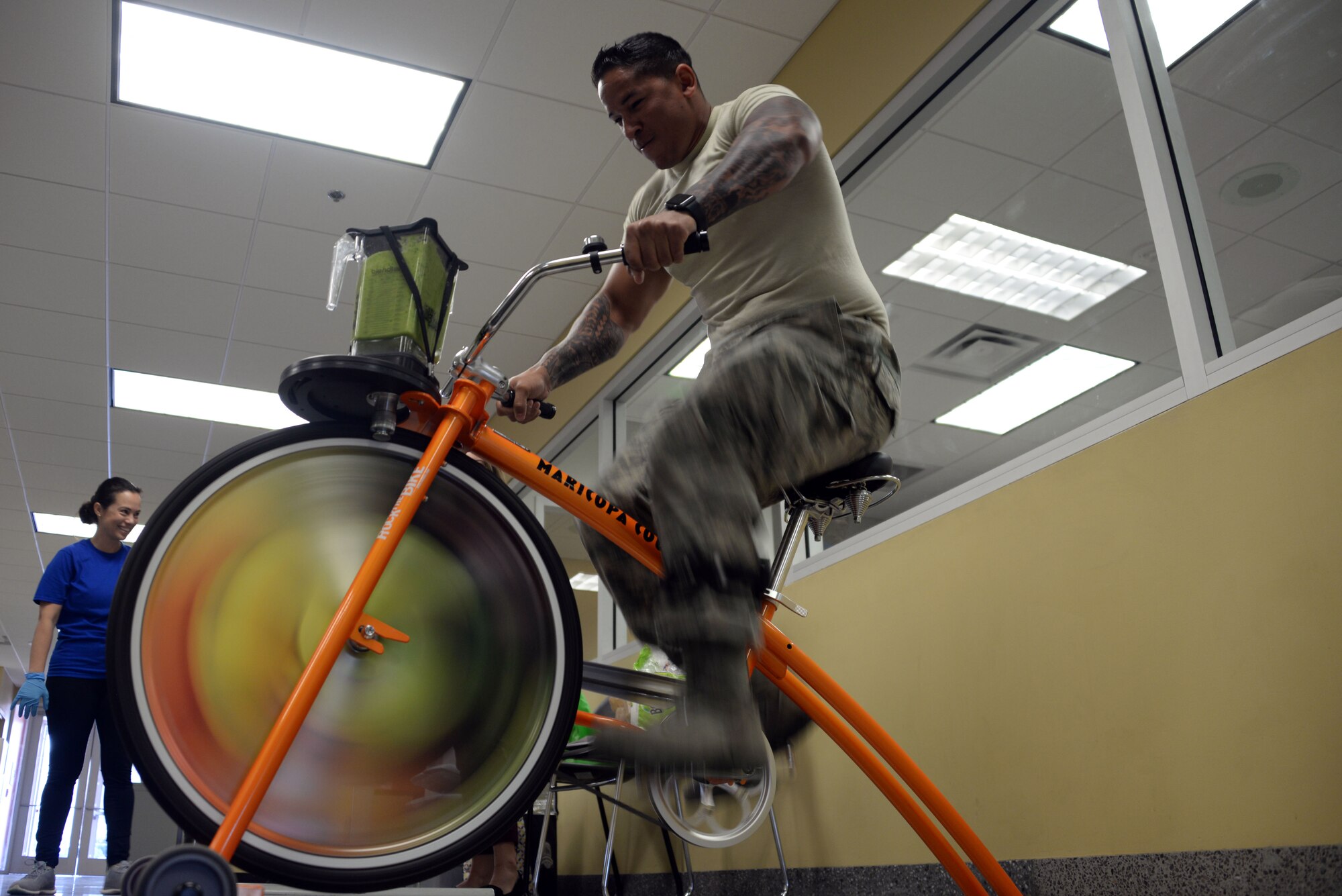 An Airman from the 62nd Aircraft Maintenance Unit powers a blender with a stationary bike during 56th Medical Group health promotion at Luke Air Force Base, Ariz., April 5, 2018. The 56th MDG is celebrating National Nutrition Month, which is themed “Go Further with Food.” The campaign focuses on the importance of making informed food choices and developing sound eating and exercising habits. (U.S. Air Force photo by Senior Airman Devante Williams)