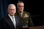 Defense Secretary James N. Mattis speaks at a lectern while Marine Corps Gen. Joe Dunford stands by.