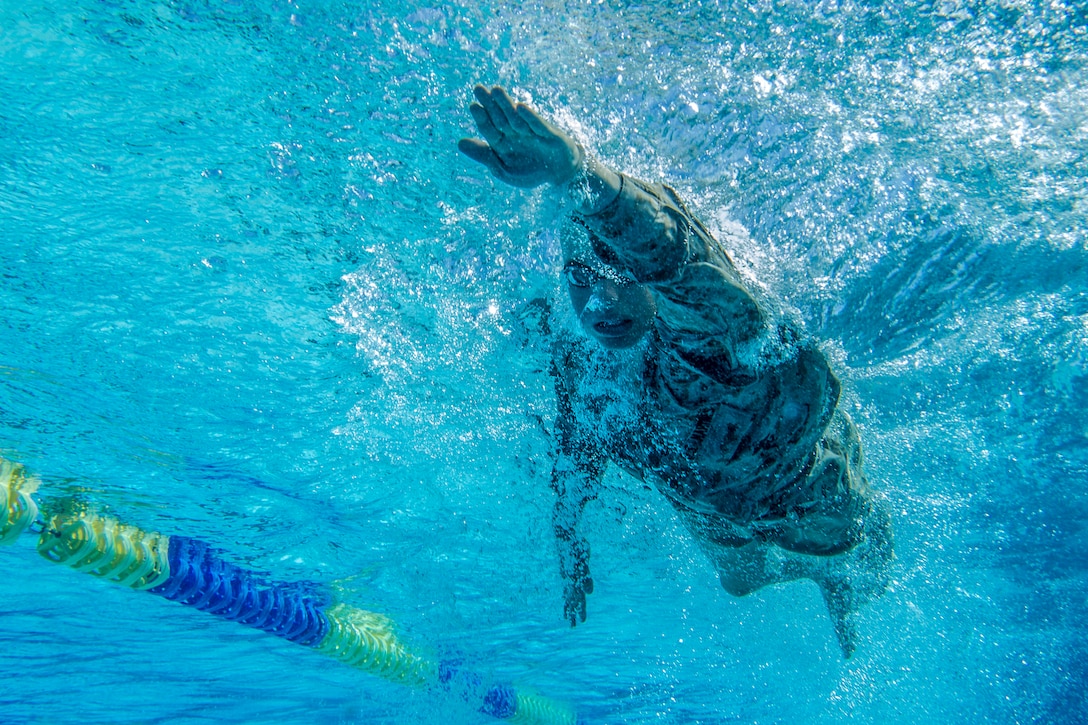 A Marine swims freestyle in a pool.