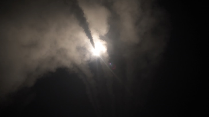 A missile launches from a ship at night. 