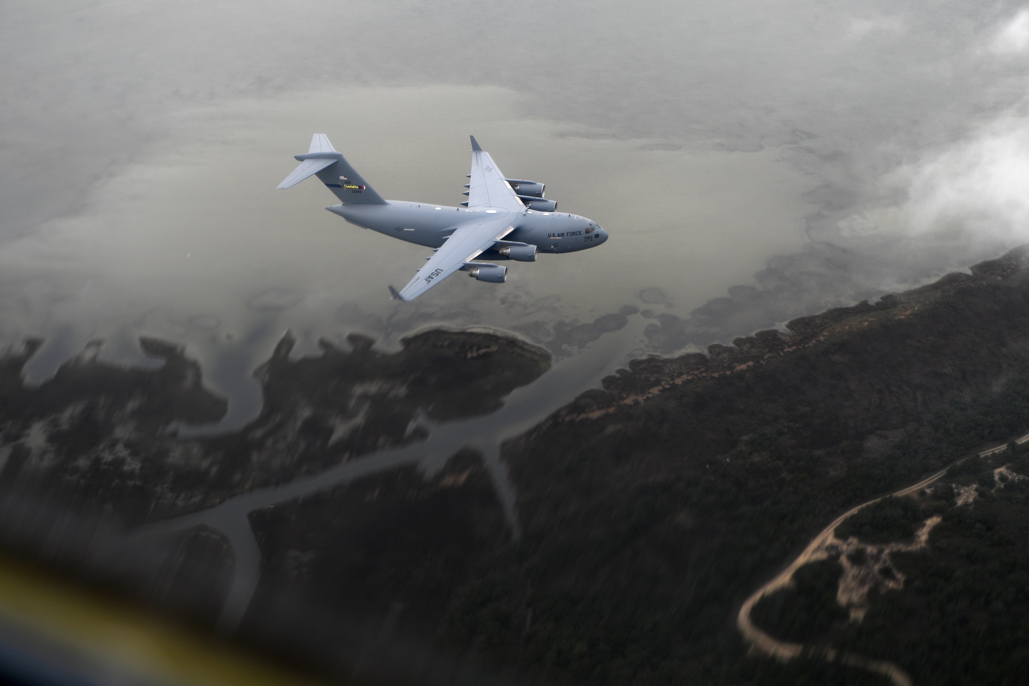 A C-17 Globemaster III aircraft flies over the N.C. coast line on the way to the North Carolina Air National Guard Base, Charlotte Douglas International Airport, April 7, 2018. The airframes homecoming will be marked by an Acceptance Ceremony. The 145th Airlift Wing (AW) was selected to transition from the C-130 Hercules aircraft to the C-17 Globemaster III aircraft 18 months ago, and the airframe will carry the units airlift mission into the future. The first two aircraft of eight to come to the 145th AW were previously assigned to the active duty wings at Joint Base Charleston, S.C. or Joint Base Lewis-McChord, Wash.