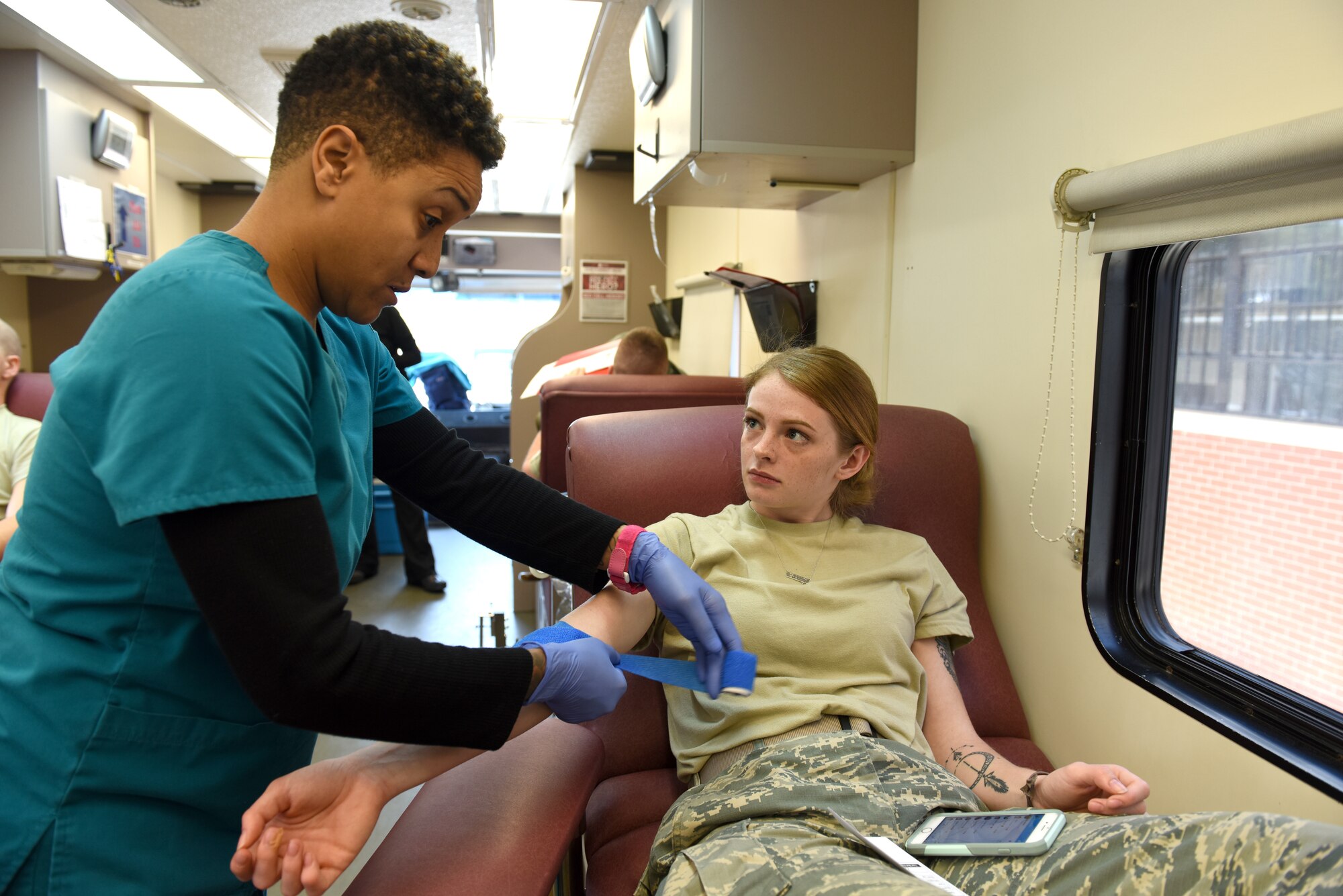 U.S. Air Force Airman First Class Kelly Wolvington (right), avionics technician with the 145th Maintenance Squadron, listens intently to directions given by Stephanie Williams (left), donor services technician with the Community Blood Center of the Carolinas (CBCC), following her blood donation in a mobile unit at the North Carolina Air National Guard (NCANG) Base, Charlotte Douglas International Airport, April 8, 2018. The CBCC has visited the base for the last four consecutive years collecting pints of blood for patients in need across North and South Carolina. (U.S. Air Force photo by Staff Sgt. Laura J. Montgomery/)