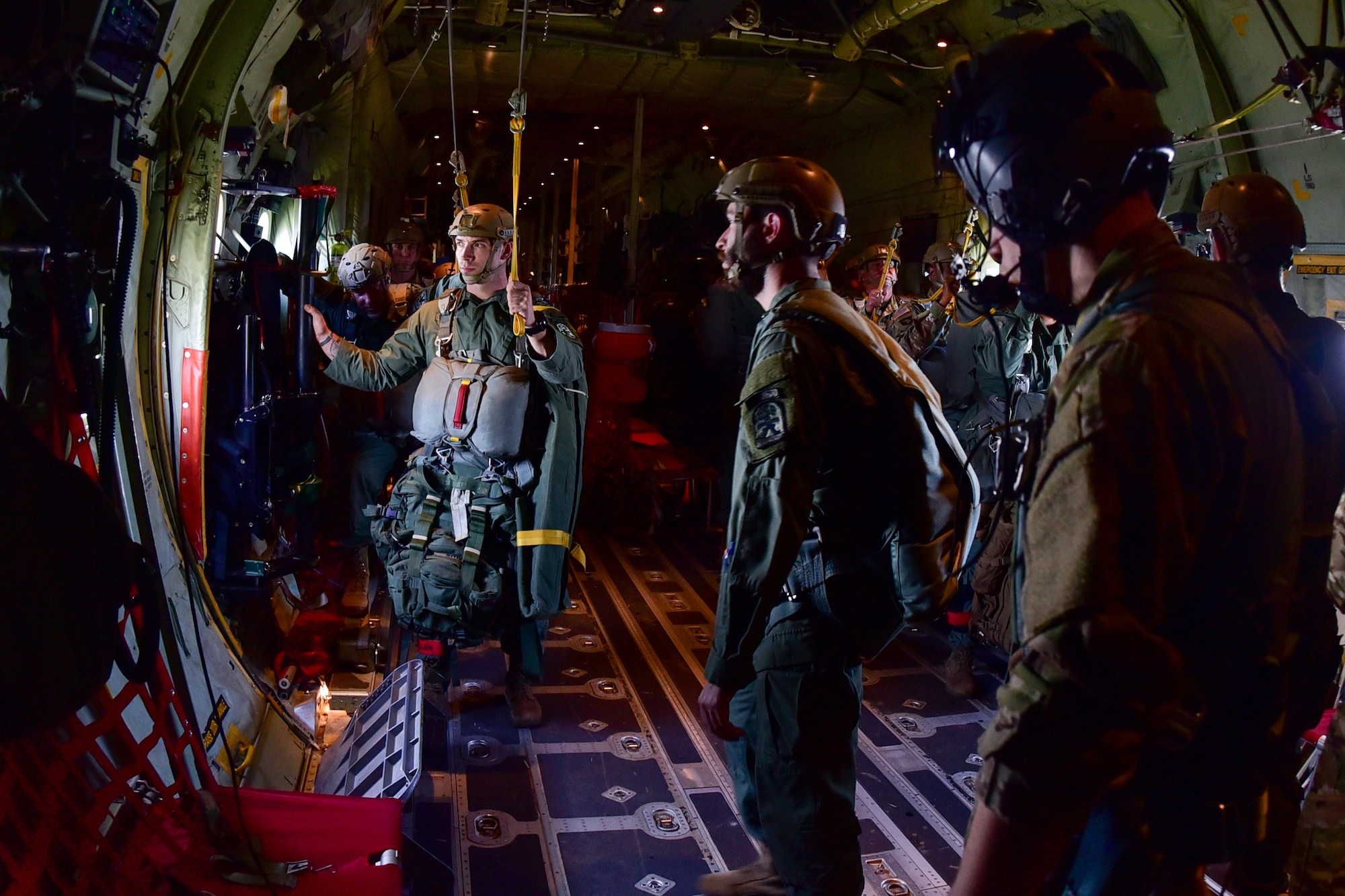Men stand in the back of a C-130J and look out of the window.