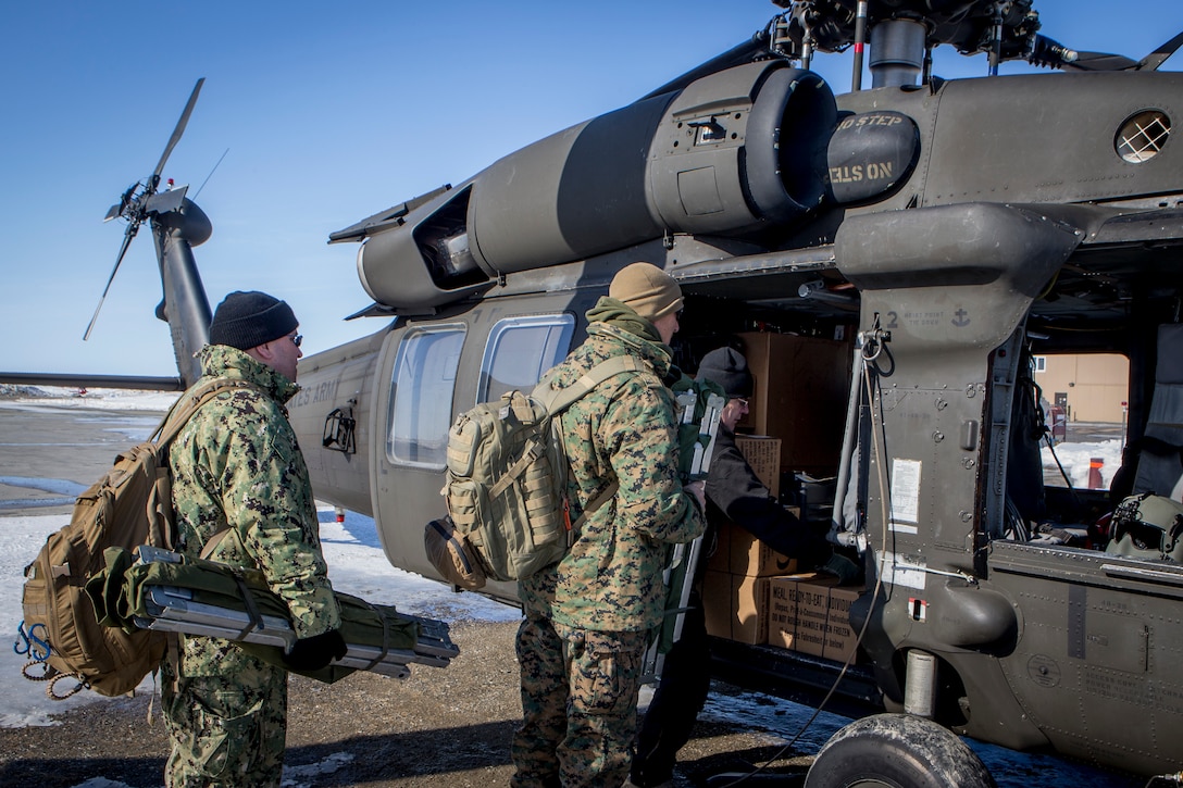 U.S. Navy personnel in support of Innovative Readiness Training Arctic Care 2018 load a U.S. Army UH-60 Black Hawk helicopter with gear and supplies as they prepare to depart Kotzebue, Alaska, and travel to outlying villages, April 13, 2018.