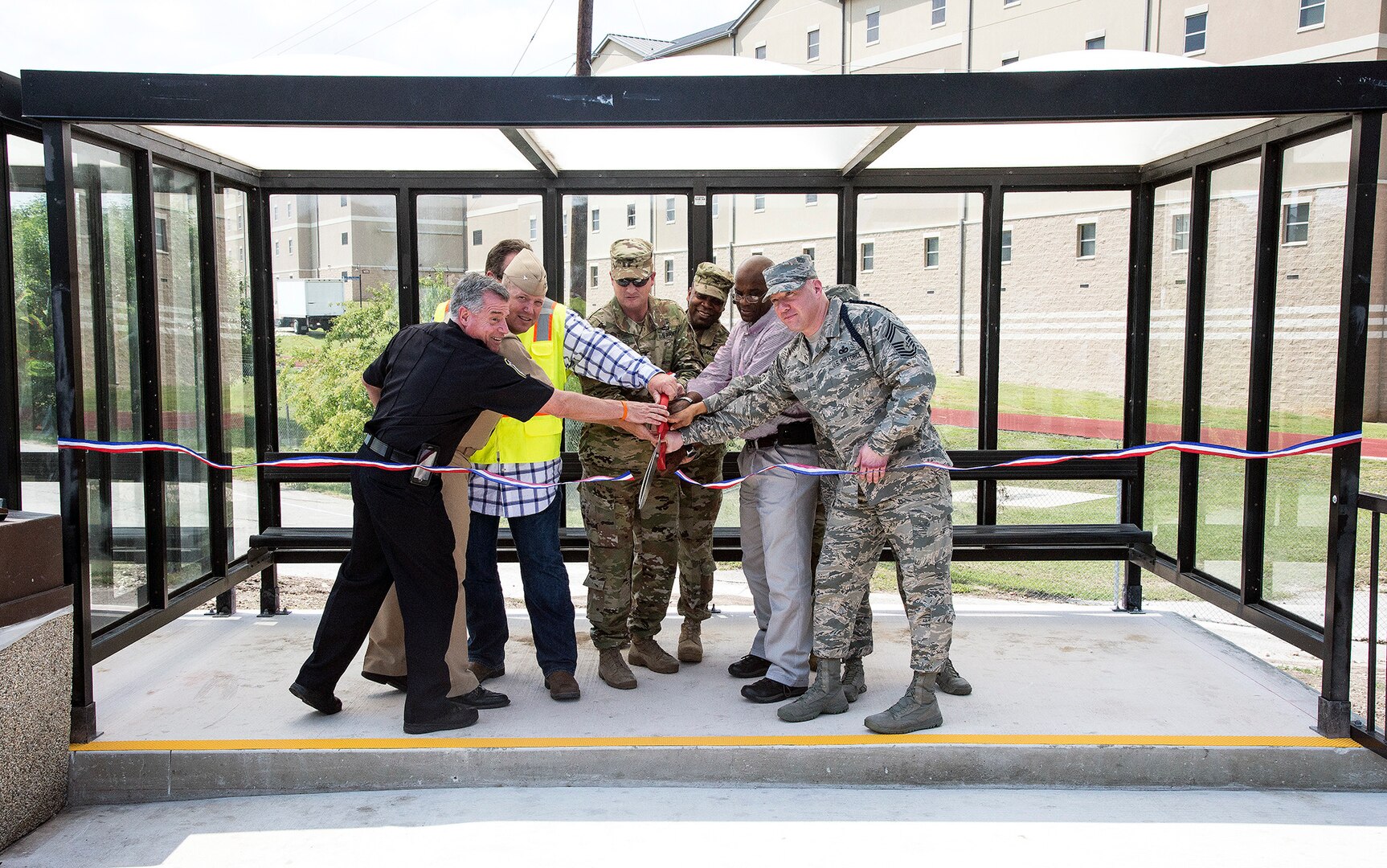 Col. Lee Flemming, 502nd Air Base Wing and Joint Base San Antonio vice commander, and Col. David Rough, 502nd Force Support Group commander, are joined by security forces, civil engineers and others to officially open the Fort Sam Houston ShareRide location April 13. The new pickup and drop-off point is located just outside the Binz-Engleman Entry Control Point.