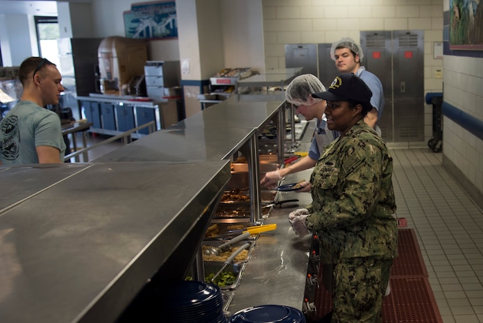 Petty Officer 1st Class Ebony Sharpe, 628th Force Support Squadron leading petty officer (LPO) in charge of JB Charleston’s weapons station galley, right, oversees the serving line, April 4, 2018.