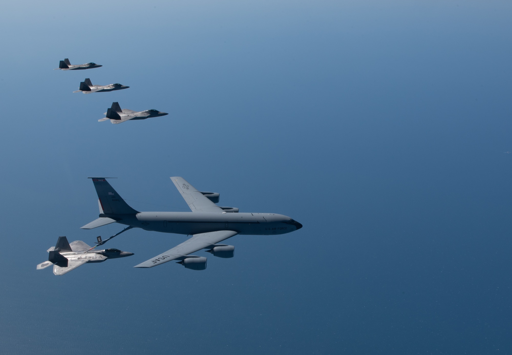 A KC-135 Stratotanker from the 121st Air Refueling Wing refuels F-22 Raptors from the 94th Fighter Squadron and 27th Fighter Squadron over the Atlantic Ocean, April 12, 2018. The 94th FS and 27th FS are the fighter squadrons of the 1st Fighter Wing at Joint Base Langley-Eustis, Va. and the 121st ARW is from Rickenbacker Air National Guard Base, Ohio. (U.S. Air Force photo by Staff Sgt. Carlin Leslie)