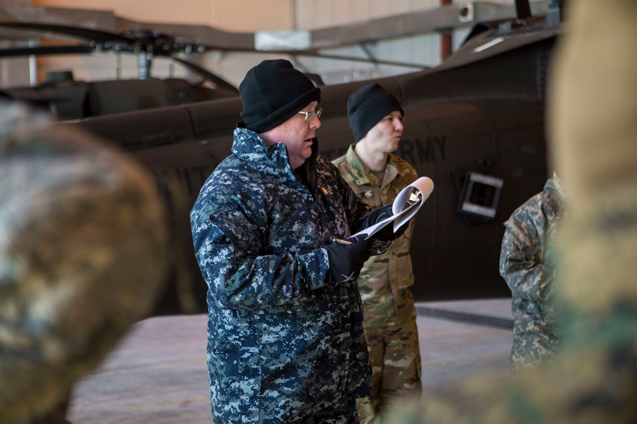 Lt. Cmrd. John Ladd, the rotary officer for IRT Arctic Care 18, provides a safety brief to service members supporting Innovative Readiness Training Arctic Care 2018 prior to boarding a U.S. Army UH-60 Black Hawk helicopter as they prepare for departure from the flight line, Kotzebue, Alaska, April 14, 2018.  IRT Arctic Care 2018 is comprised of a joint and multi-national force providing medical, dental, optometry and veterinary care for underserved villages in the Maniilaq Service Area, April 16-24. (U.S. Marine Corps photo by Lance Cpl. Ricardo Davila