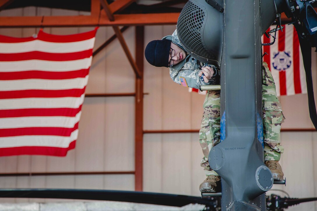An airman holds onto the tail of a helicopter.