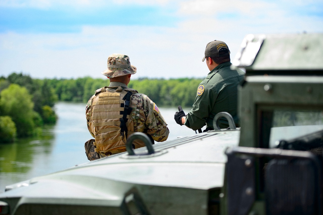 A Texas National Guardsman and a Customs and a Border Protection agent discuss the border security mission on the shores of the Rio Grande River.