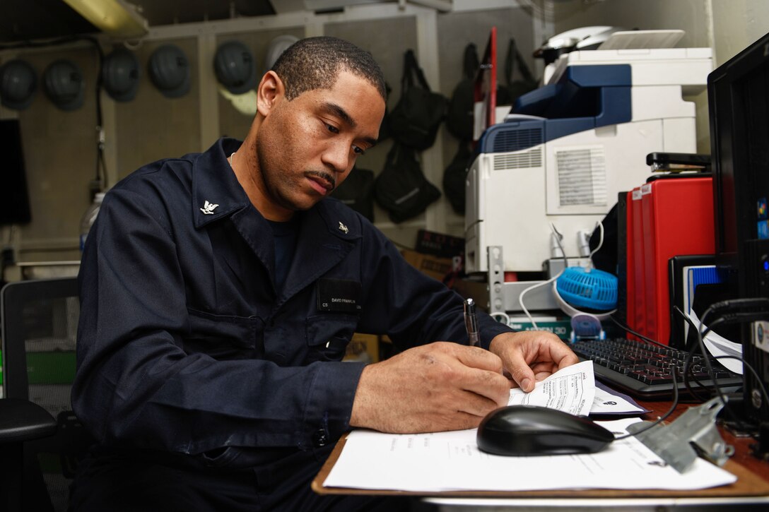 A sailor checks maintenance paperwork.