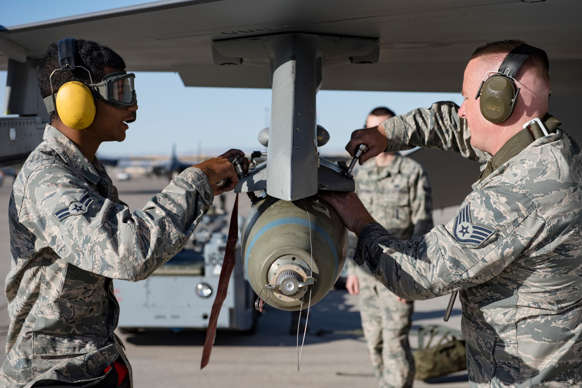 Airman 1st Class Geoffrey Saunders and Staff Sgt. Shawn White, 57th Aircraft Maintenance Squadron weapons loaders, load a bomb onto an F-16 Fighting Falcon fighter jet during a load crew competition at Nellis Air Force Base, Nevada, April 13, 2018. Load crew competitions provide weapons loaders throughout the 57th MXG the opportunity to display their weapons loading skills to their peers and superiors.(U.S. Air Force photo by Airman 1st Class Andrew D. Sarver)