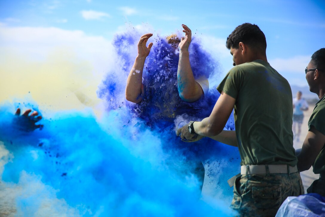 A Marine is  covered in colored powdered as he passes a color station during the Sexual Assault Prevention and Response annual Colorful Consent Run held aboard the Marine Corps Air Ground Combat Center, Twentynine Palms, Calif., April 6, 2018. The goal of the 5k color fun run was to have everyone gather to spread awareness while still having fun. (U.S. Marine Corps Photo by Cpl. Christian Lopez)