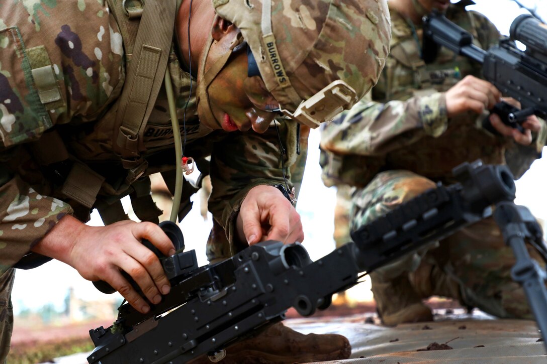 A soldier reattaches a scope to a machine gun.