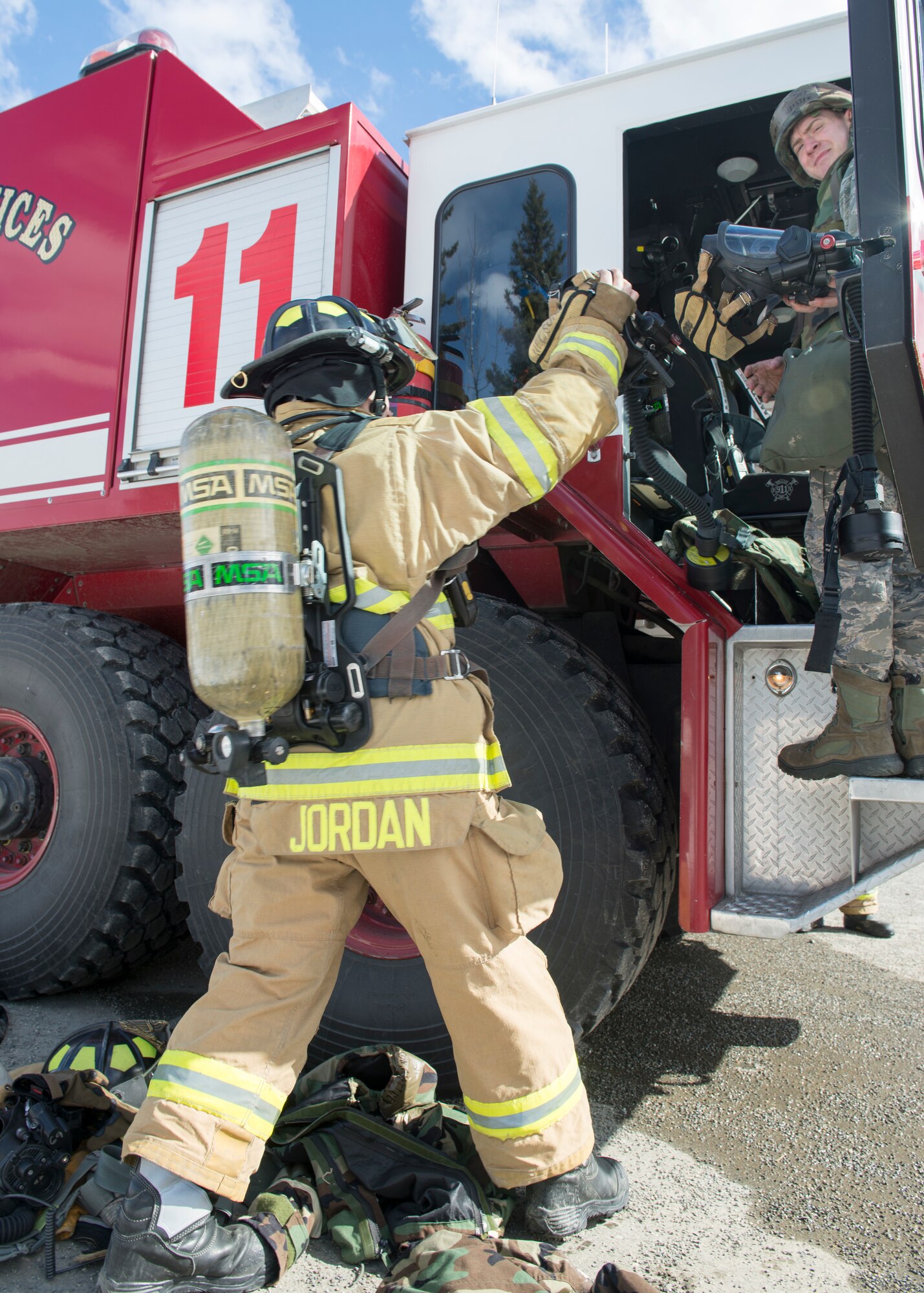 Senior Airmen William White passes a self-contained breathing apparatus to Airmen 1st Class Brittney Jordan, both Airmen are 673d Civil Engineer Squadron Fire and Emergency Service driver/operators, during exercise Polar Force 18-5 at Joint Base Elmendorf-Richardson, Alaska, April 11, 2018. Throughout the routine training exercise, Airmen donned Mission Oriented Protective Posture gear while completing various mission-related tasks to test their capabilities in challenging circumstances.