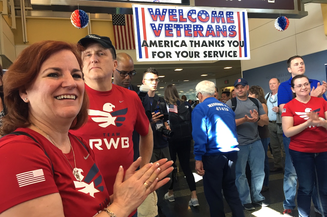 Members of Team Red, White and Blue, clap for arriving veterans.