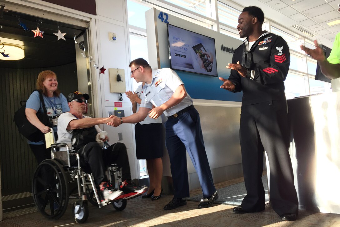 A Coast Guardsmen shakes hands with a veteran as he arrives.