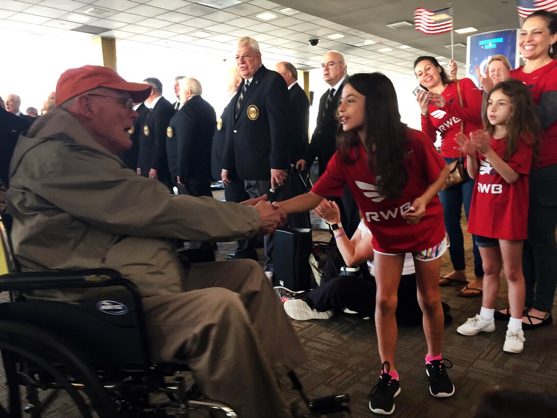 A member of Team Red, White and Blue shakes hands with a veteran.