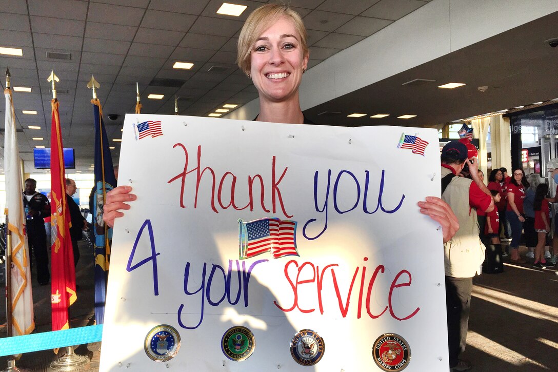 A volunteer holds a sign thanking veterans.