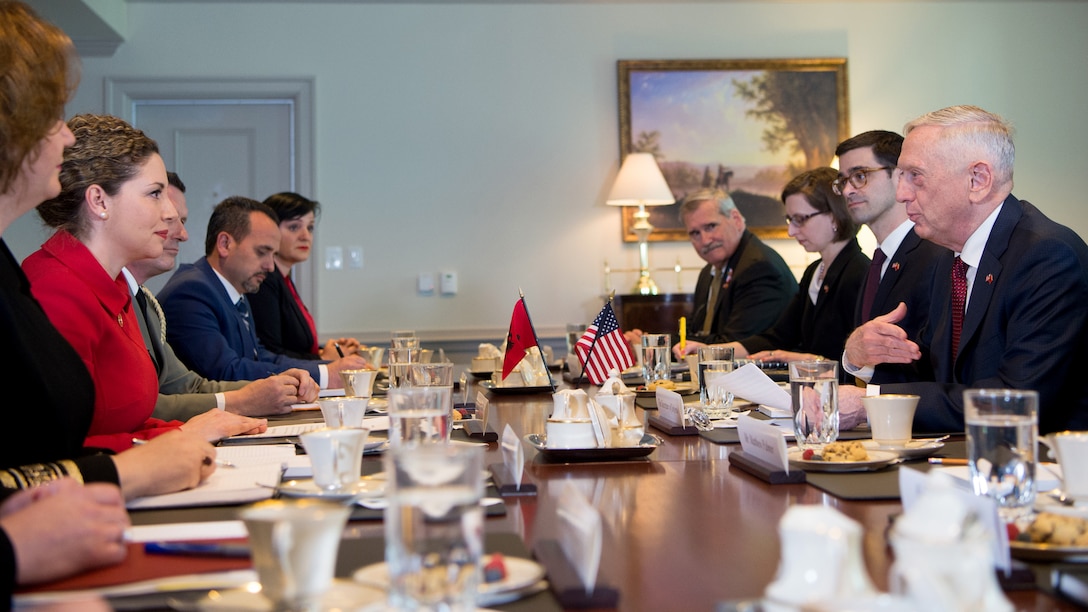 Defense Secretary James N. Mattis sits at a table with other people.